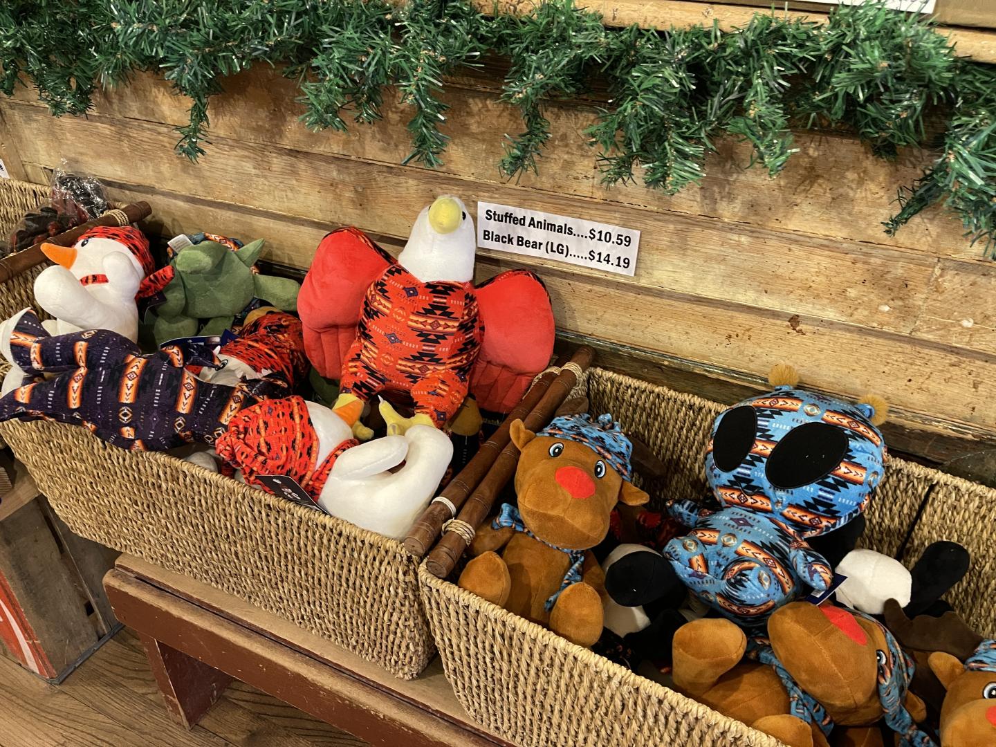 Plush toys in baskets beneath festive greenery.