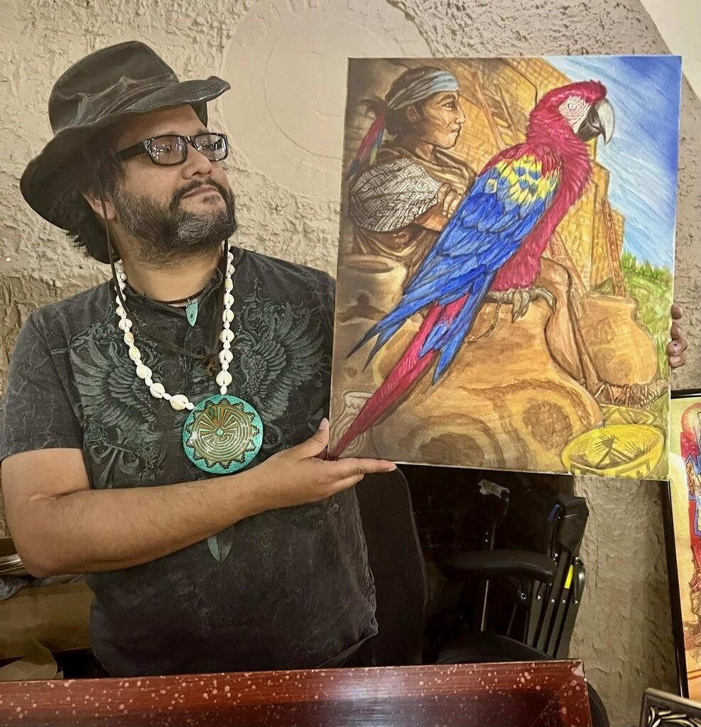 Man in hat holding colorful parrot painting in art gallery setting.