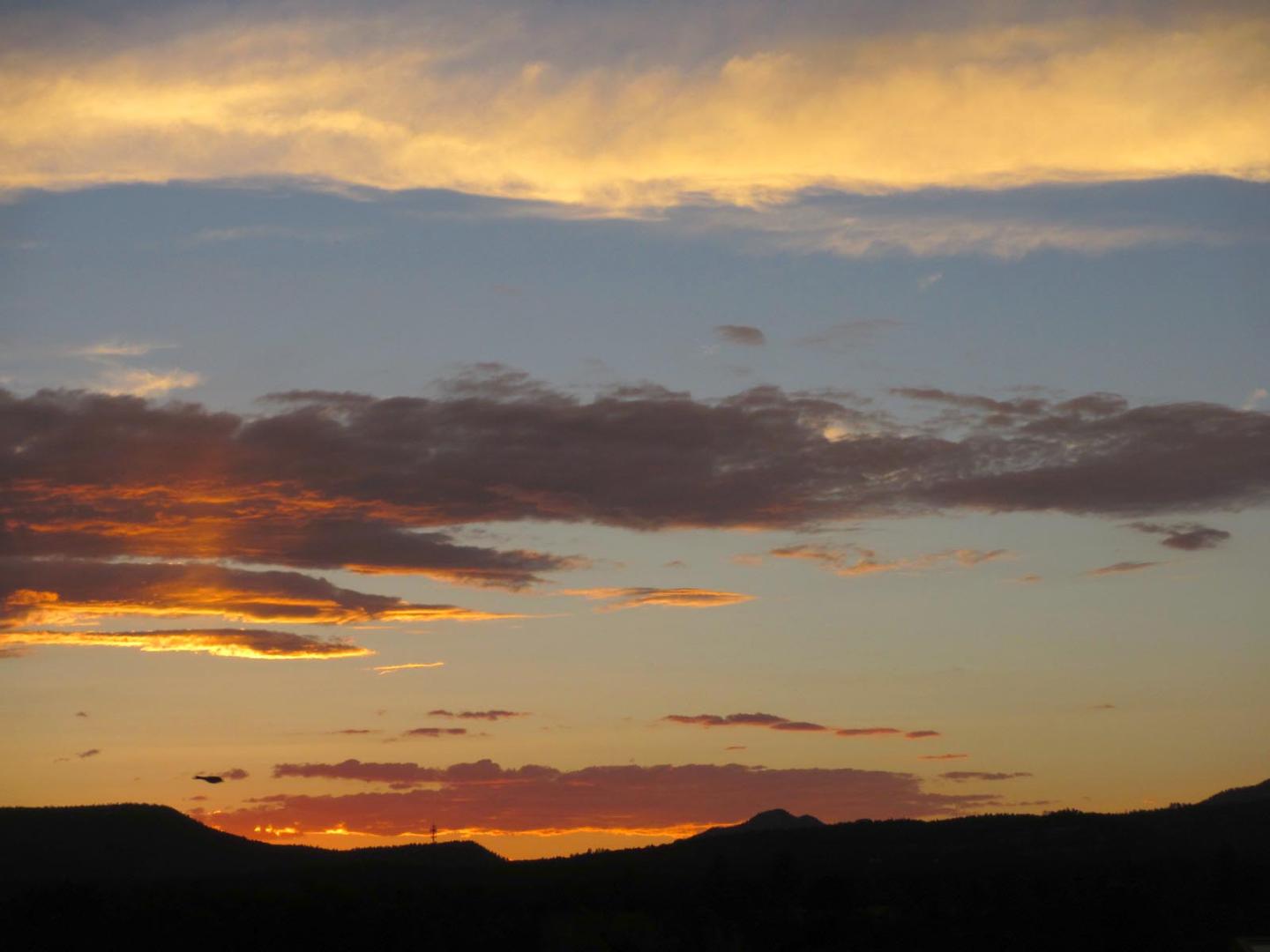 Sunset with orange and pink clouds over dark mountains.