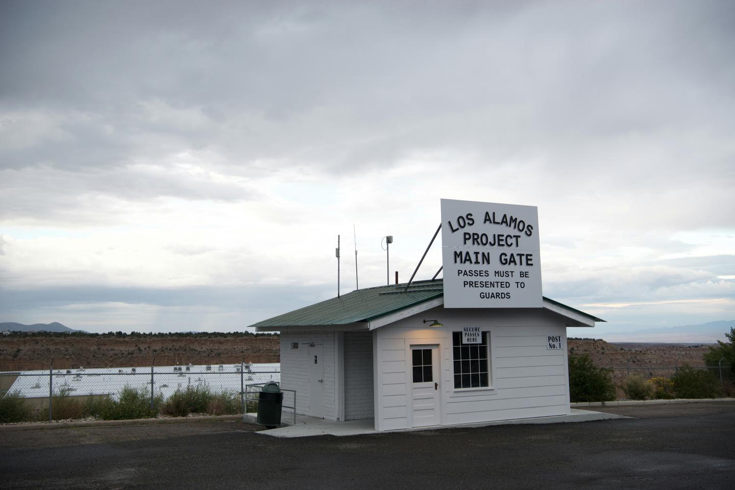 Small white building under cloudy sky with a sign on the roof.