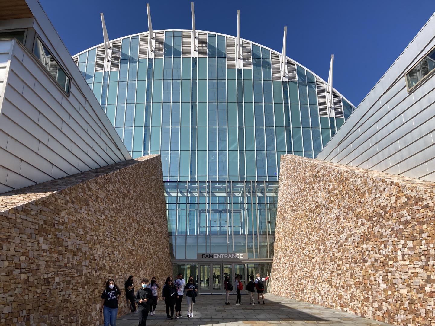 Modern glass building with stone walls, blue sky.