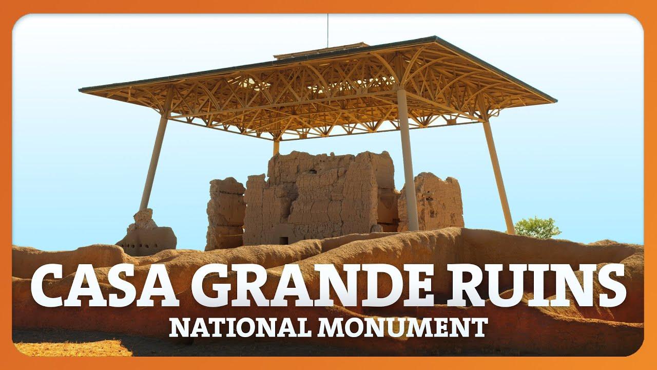 Casa Grande Ruins under a protective metal roof against a clear sky.