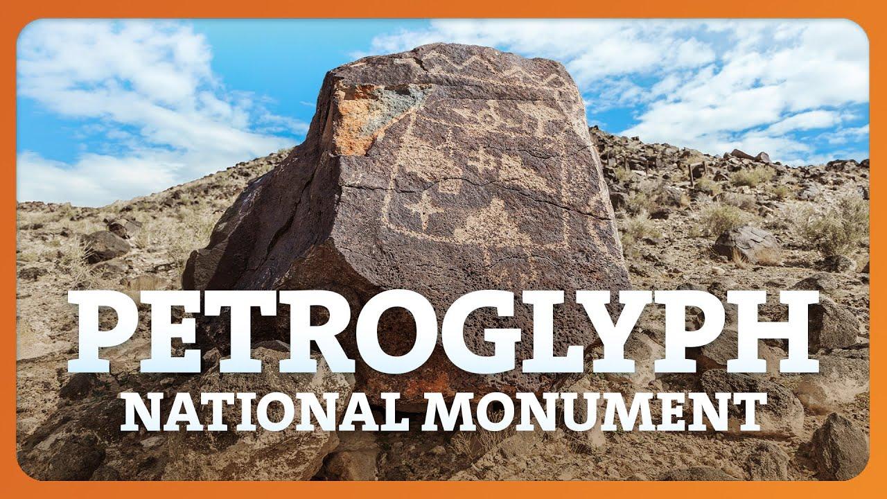 Rock with ancient carvings under blue sky, desert landscape.
