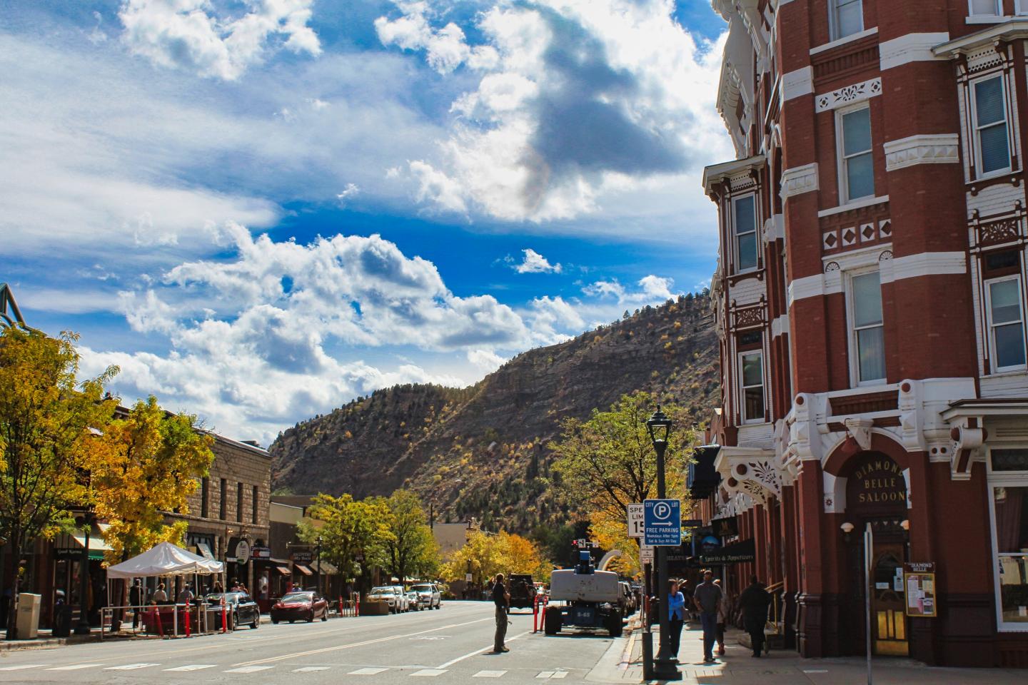 Street view with red brick building, mountains, and blue sky with clouds.