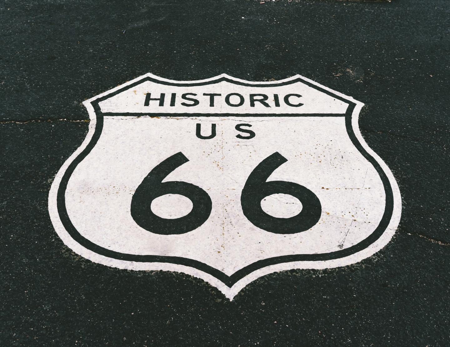 Historic US Route 66 road sign on asphalt.