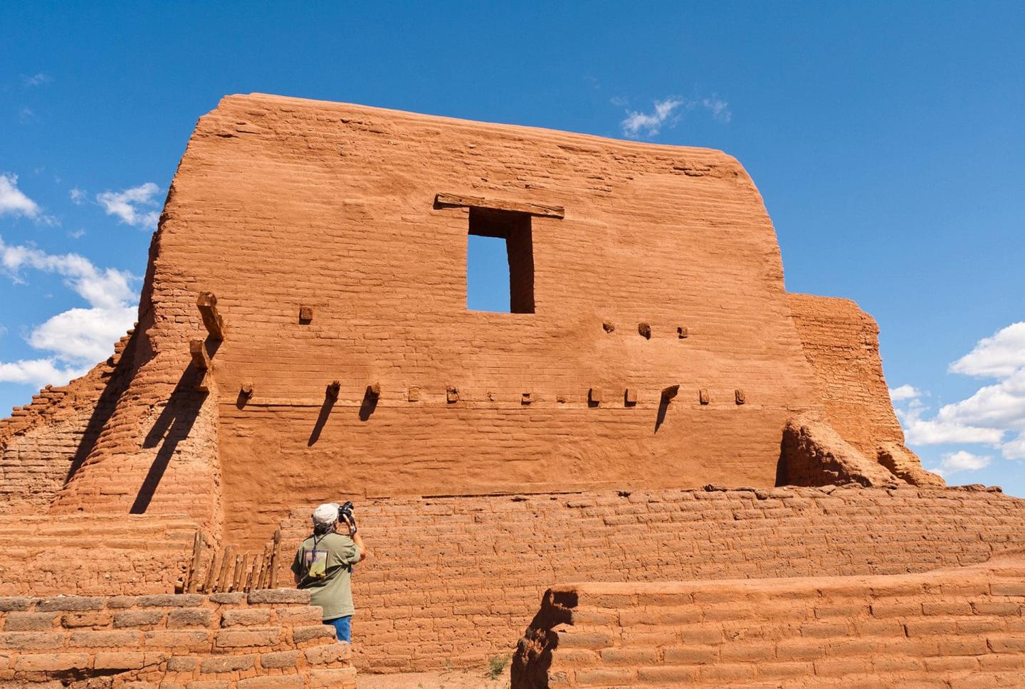 Ancient adobe ruins under a blue sky with scattered clouds.