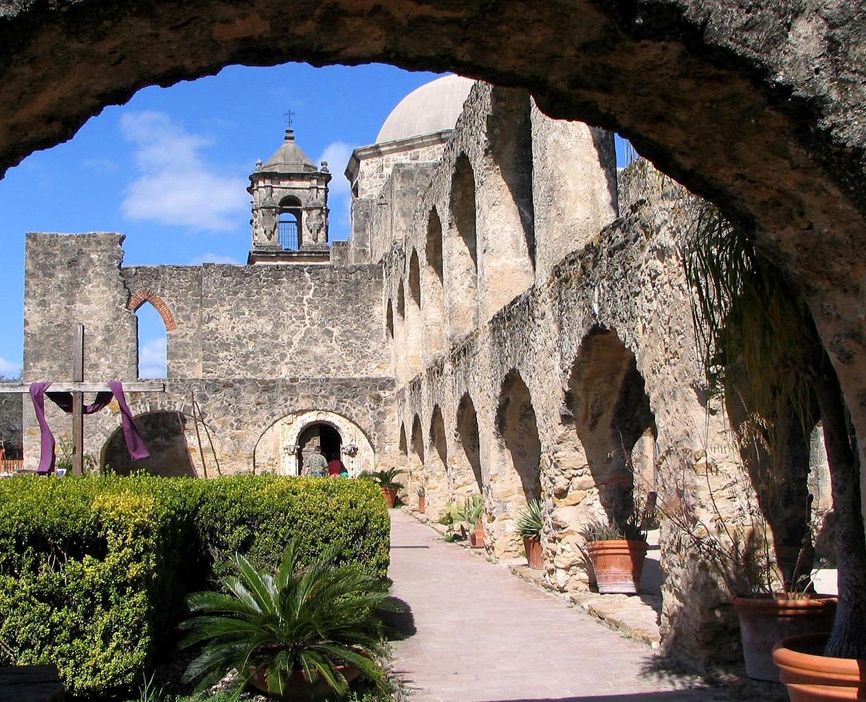 Historic stone arches with plants and blue sky.