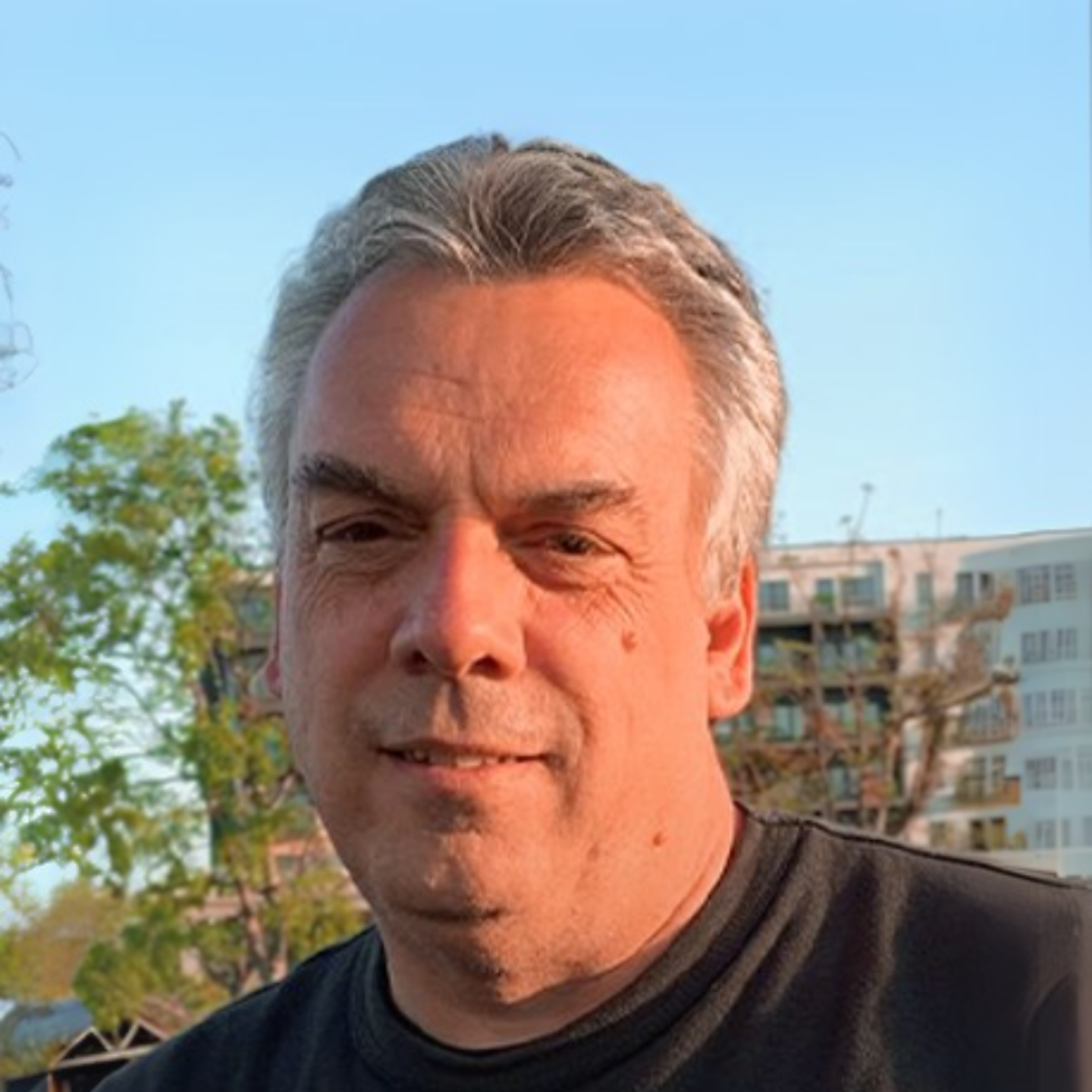 William Gibson Parker, 2024 recipient of Emil W. Haury Lifetime Achievement Award in front of trees, blue sky, and buildings at sunset.