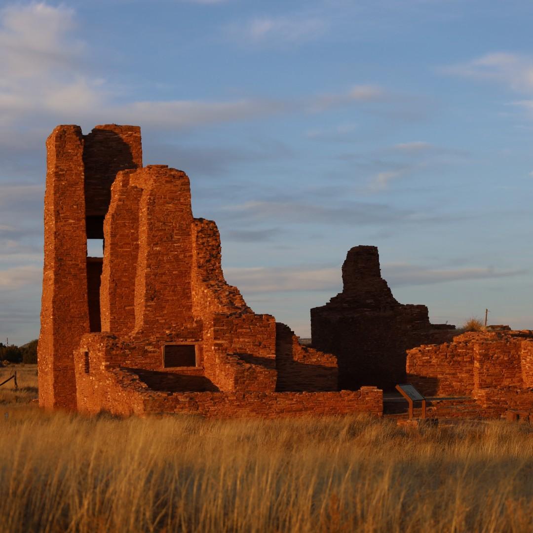 Ancient red brick ruins under a blue sky at sunset.