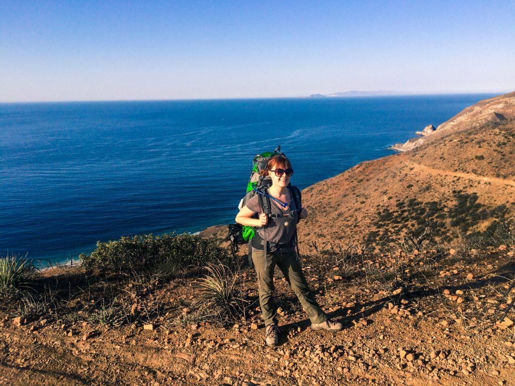 Emily Pennington on Backbone Trail at Santa Monica Mountains National Recreation Area in front of a blue ocean and blue sky.
