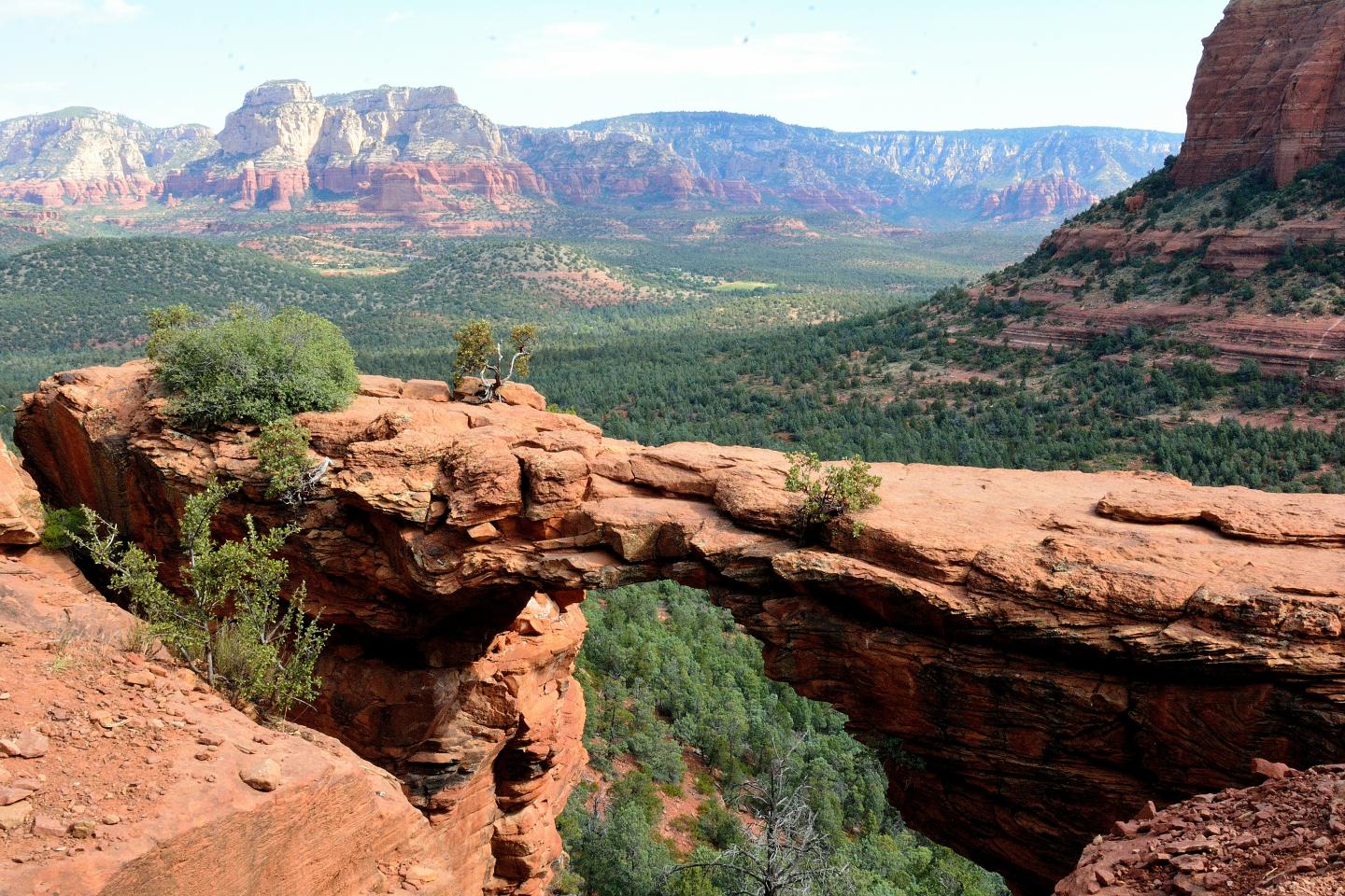 Red rock arch with vast mountain landscape in the background.