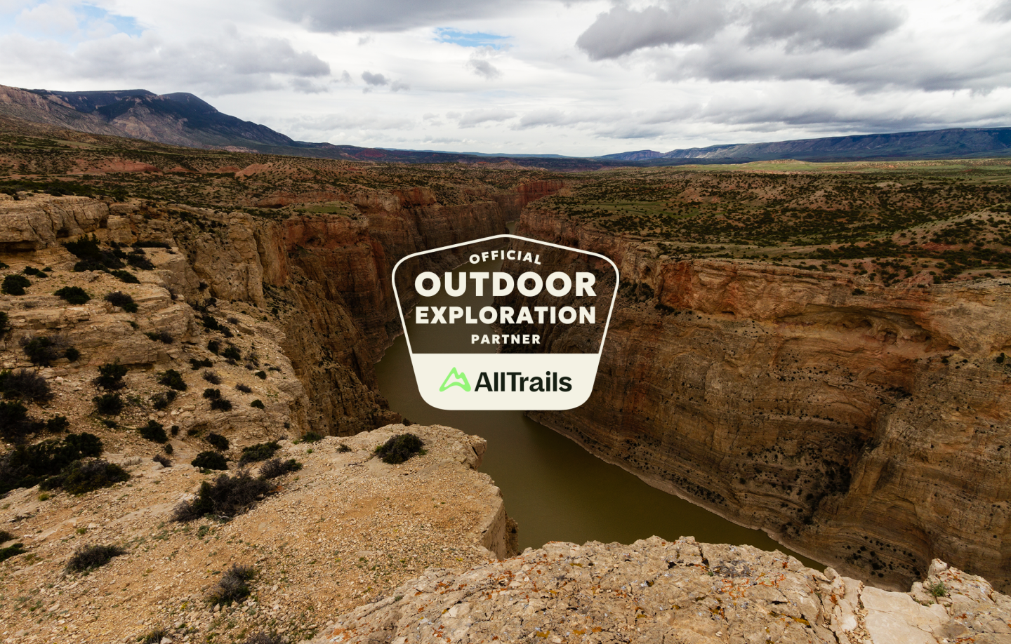 Canyon landscape under cloudy sky with a badge for AllTrails.