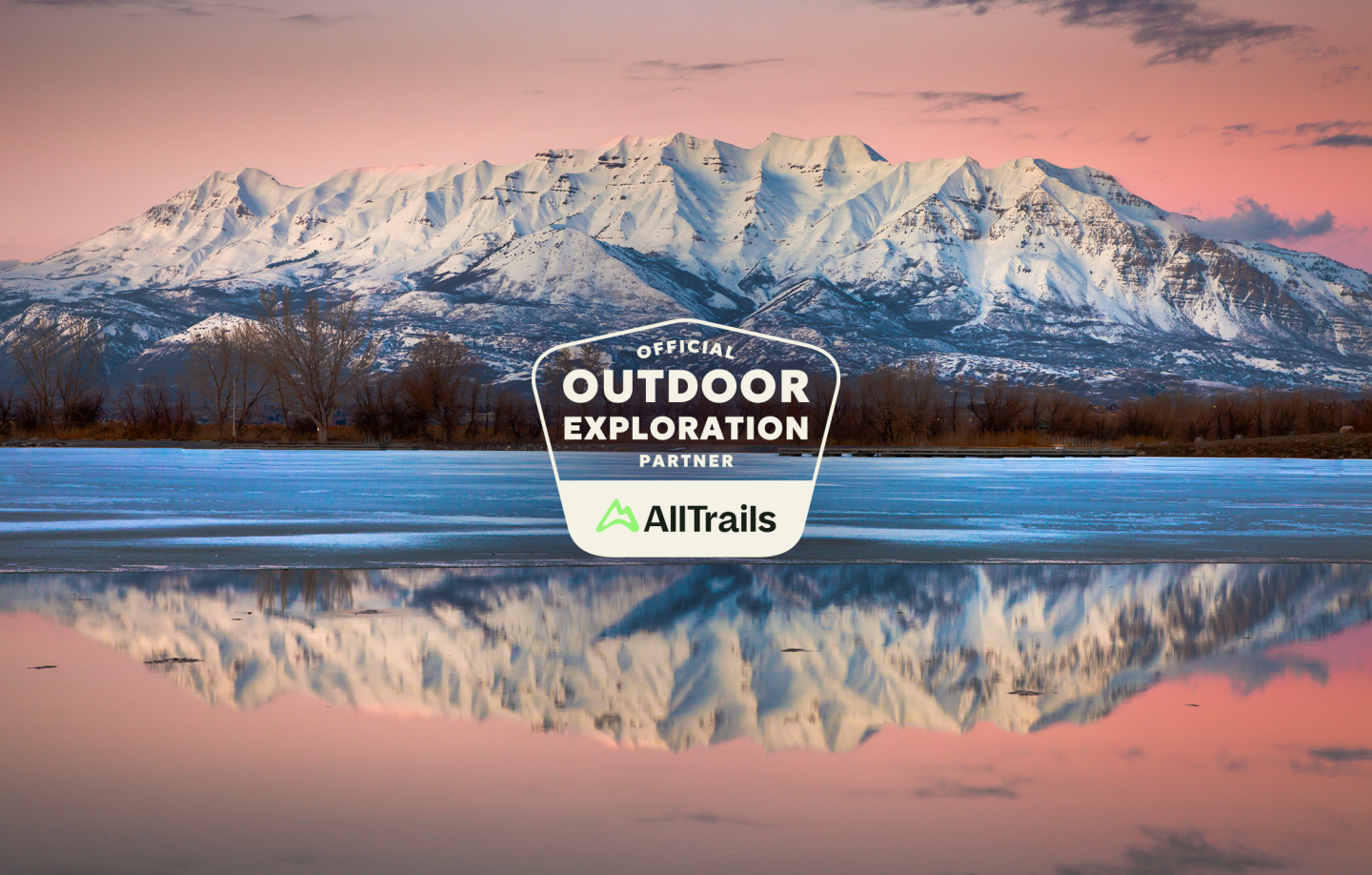 Snowy mountain reflected in a calm lake at sunset.