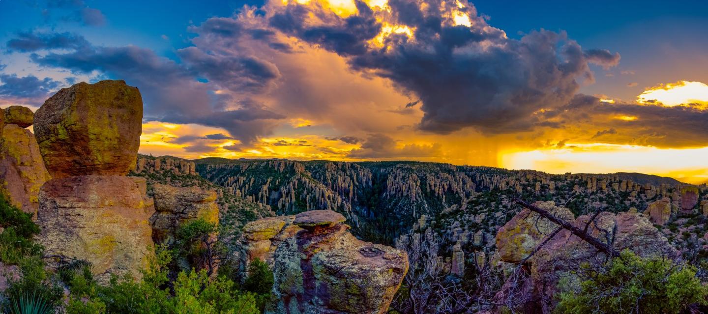 Dramatic sunset over a rocky canyon with colorful clouds and vibrant sky.