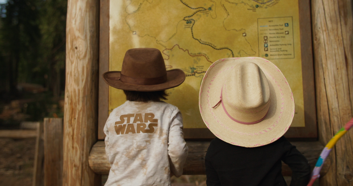 Two children in cowboy hats look at a park map.