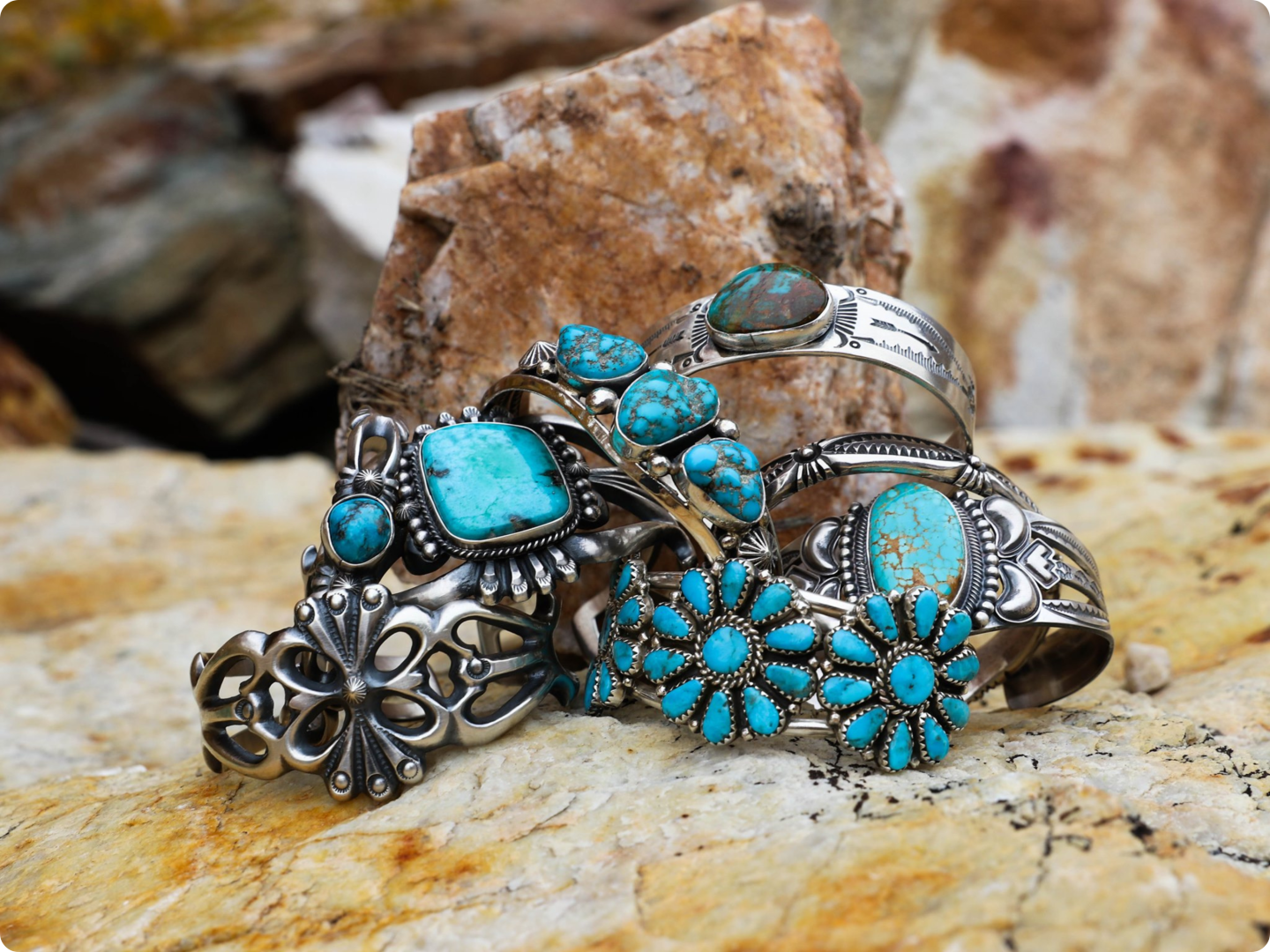 Silver and turquoise jewelry on a rocky surface.