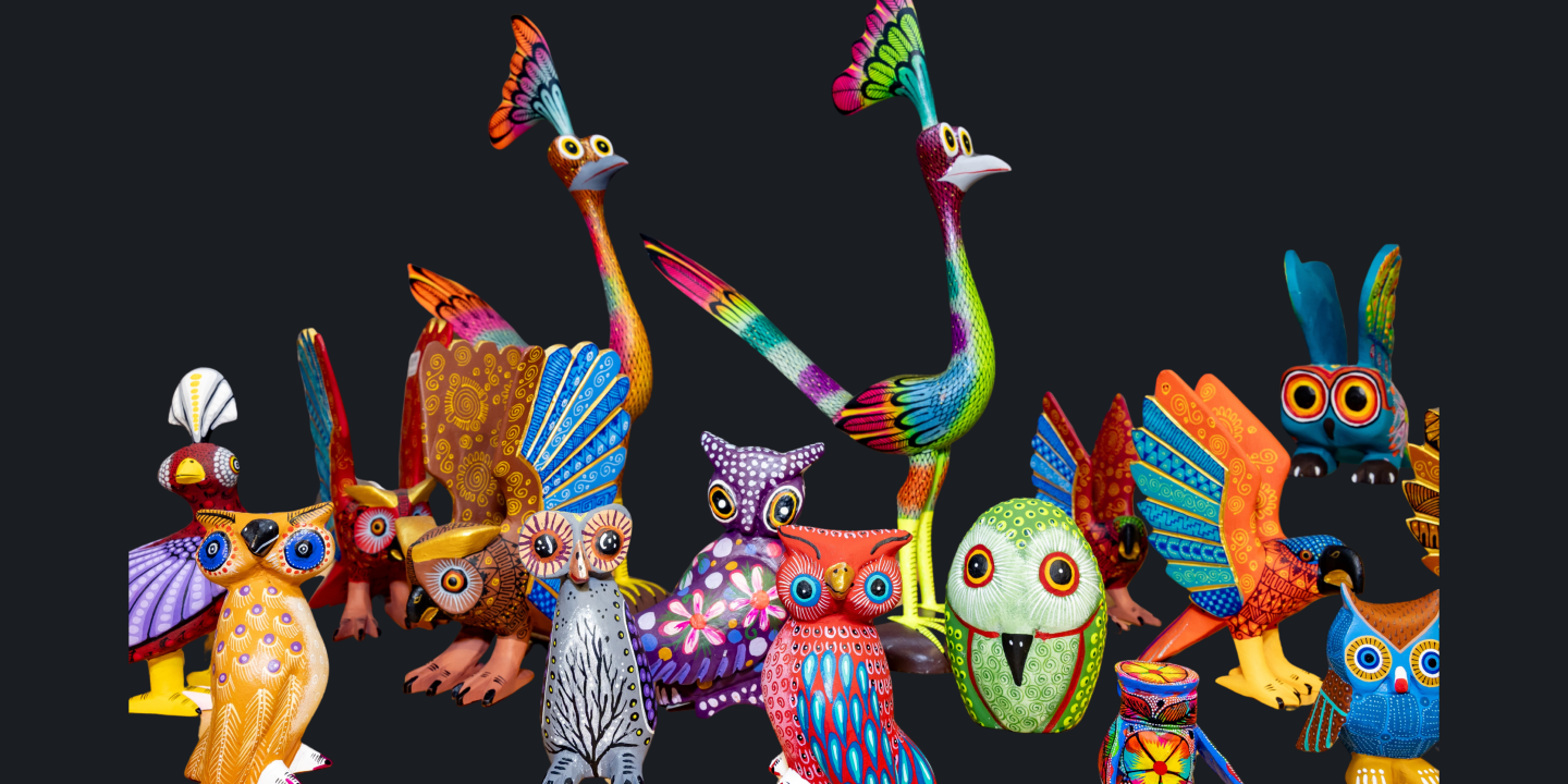 Colorful, hand-painted owl and bird carved figurines or "alebrijes" on a dark background.