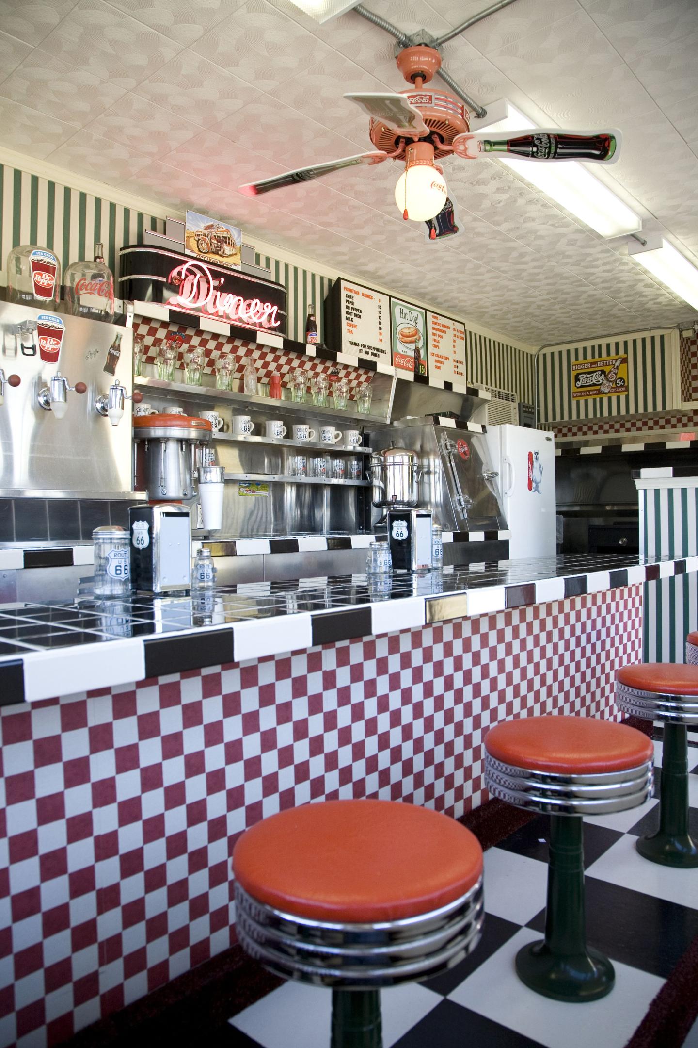 Retro diner interior with red stools and checkered counter.