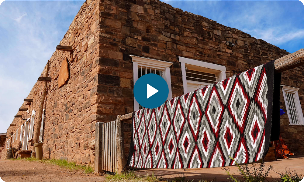 Old stone building with diamond-patterned blanket hanging outside.