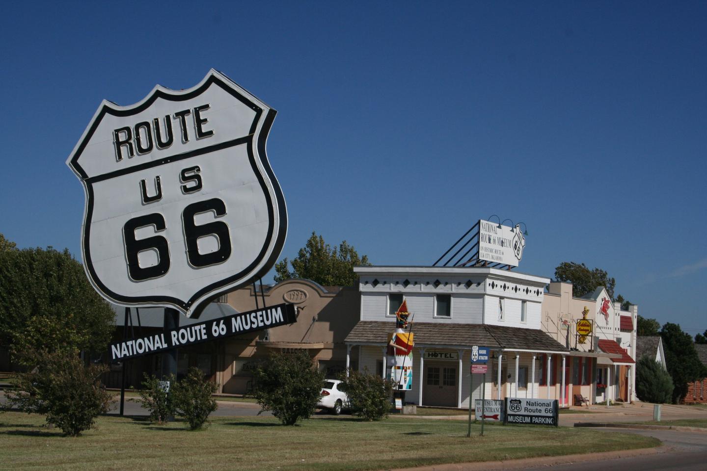 Route 66 sign near vintage-style diners under a clear blue sky.