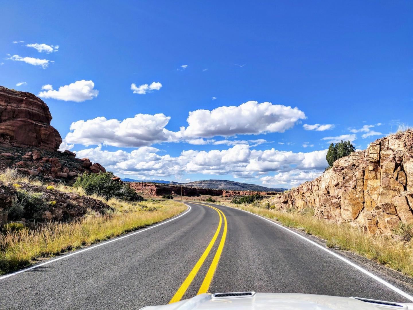 Curving road through rocky desert landscape under a bright blue sky.