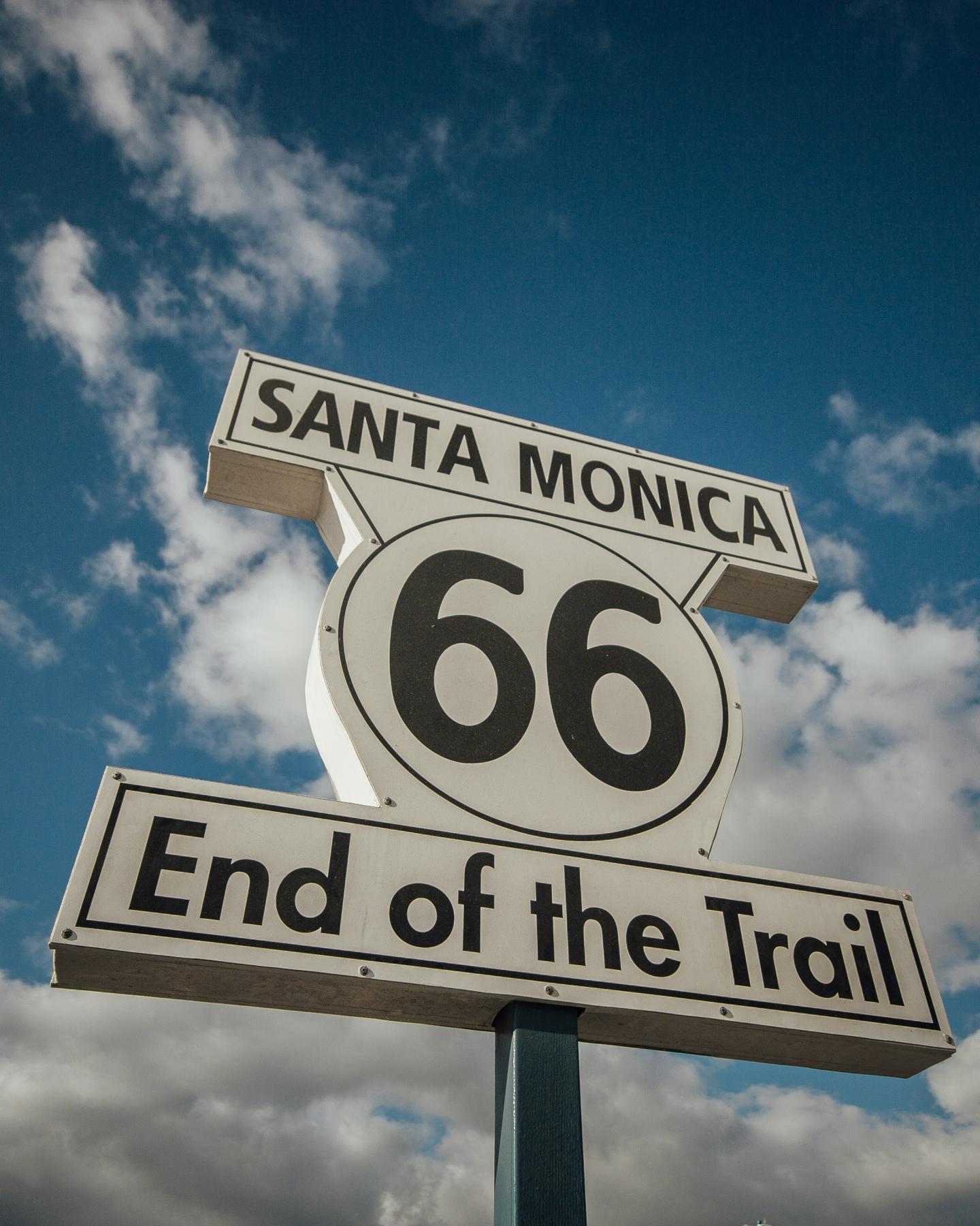 Route 66 sign with blue sky and clouds.