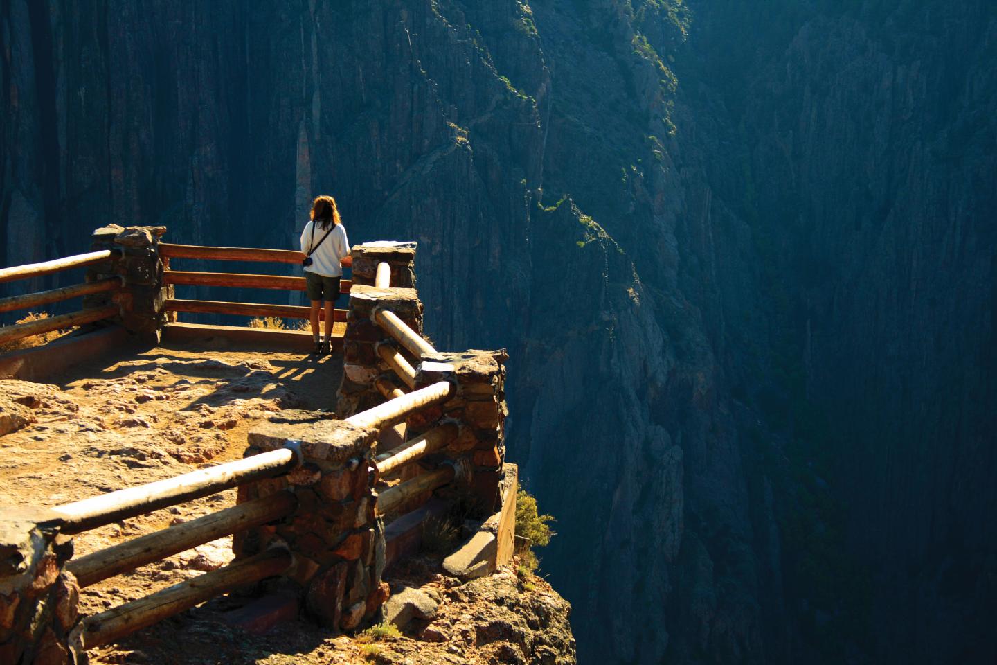 Woman standing on a cliff edge, overlooking a deep canyon.