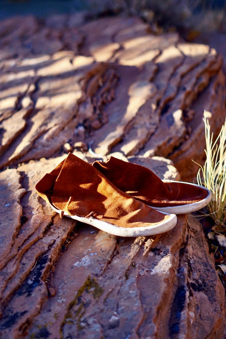 Brown leather shoes on a textured rock surface.