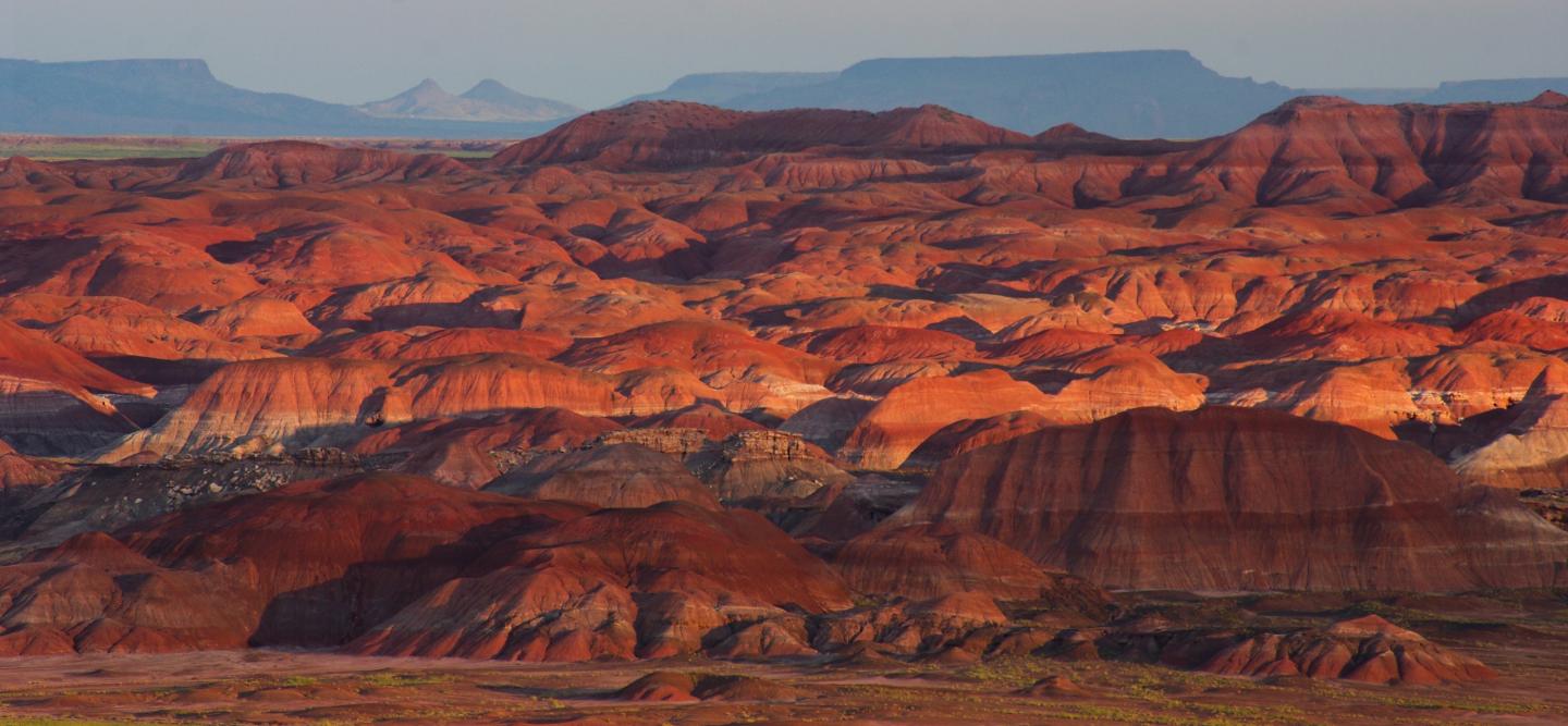 Colorful layered hills at sunset in a desert landscape.