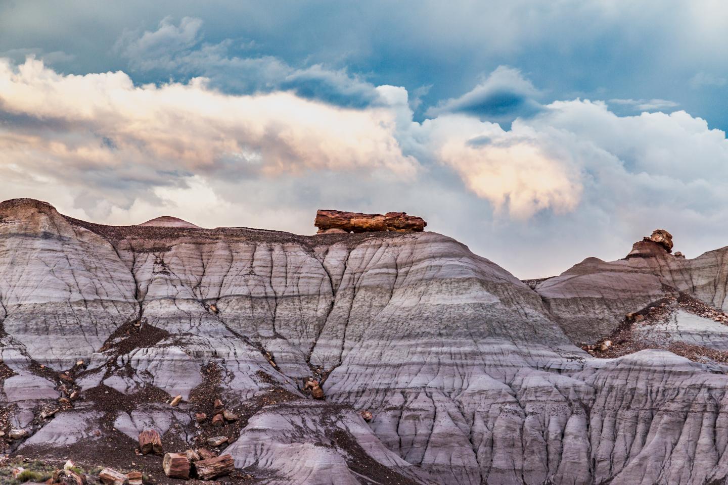 Layered rock formations under a cloudy blue sky.