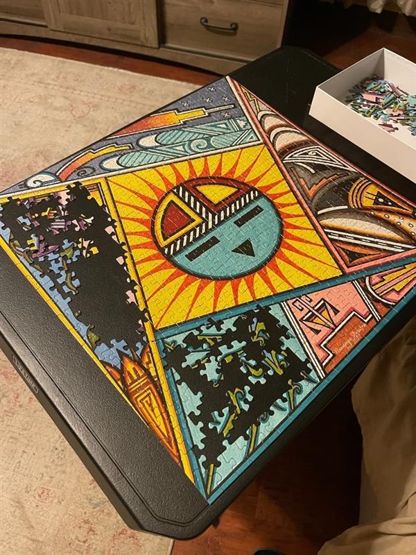 Colorful, geometric puzzle with a sun design on a black table.