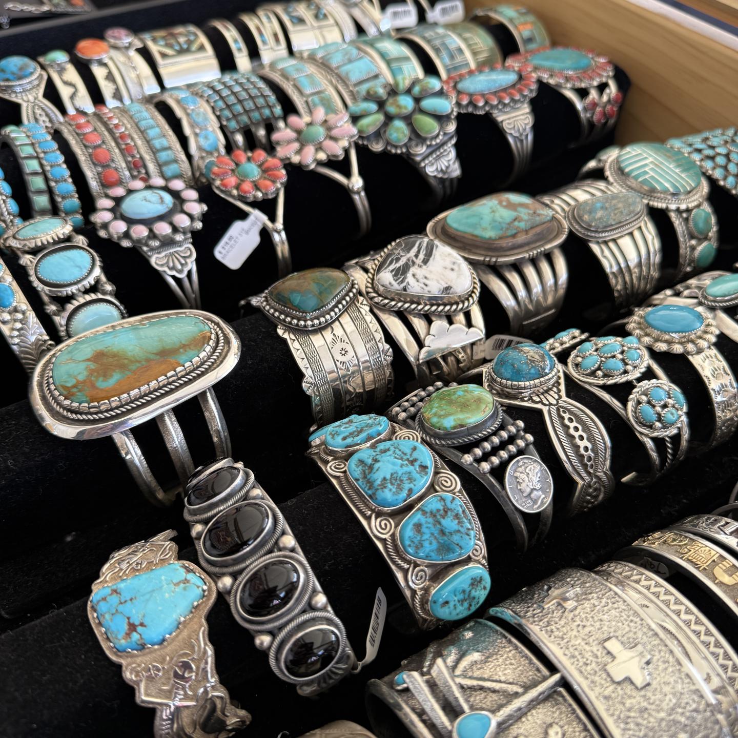 Silver bracelets with turquoise stones displayed on black velvet.
