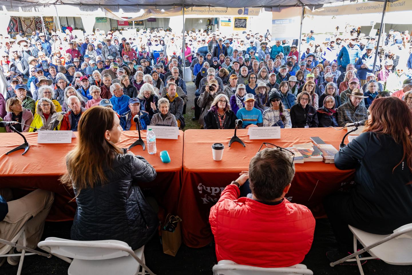 Panel discussion with three speakers, facing a large, attentive audience.
