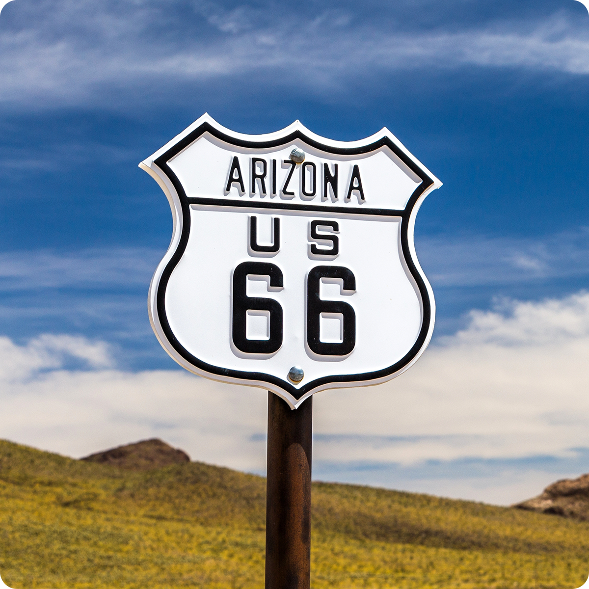 Route 66 sign under blue sky in Arizona desert.