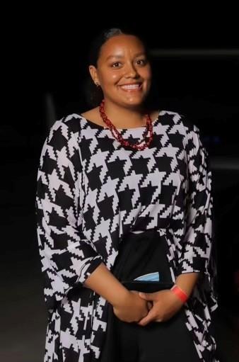 Smiling woman in a black-and-white patterned dress at night.