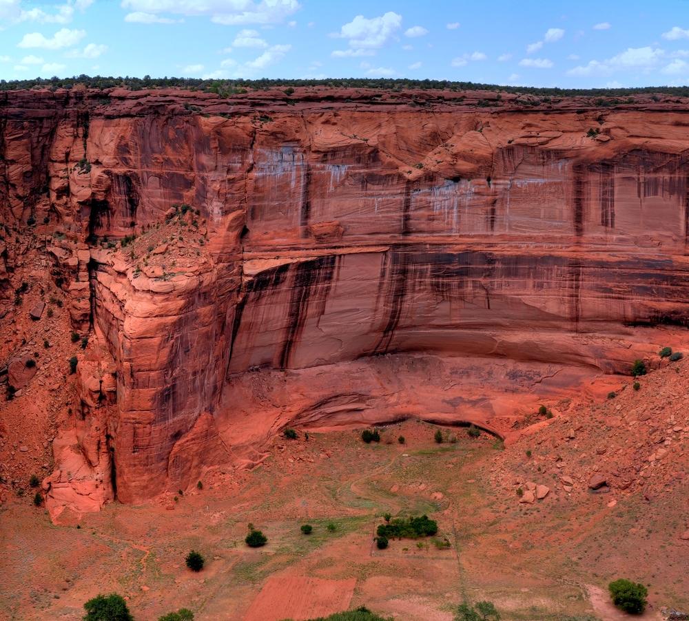 Red cliffs under a blue sky with scattered clouds.