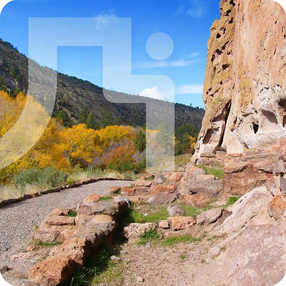 Rocky cliffside path with autumn trees under a clear blue sky.
