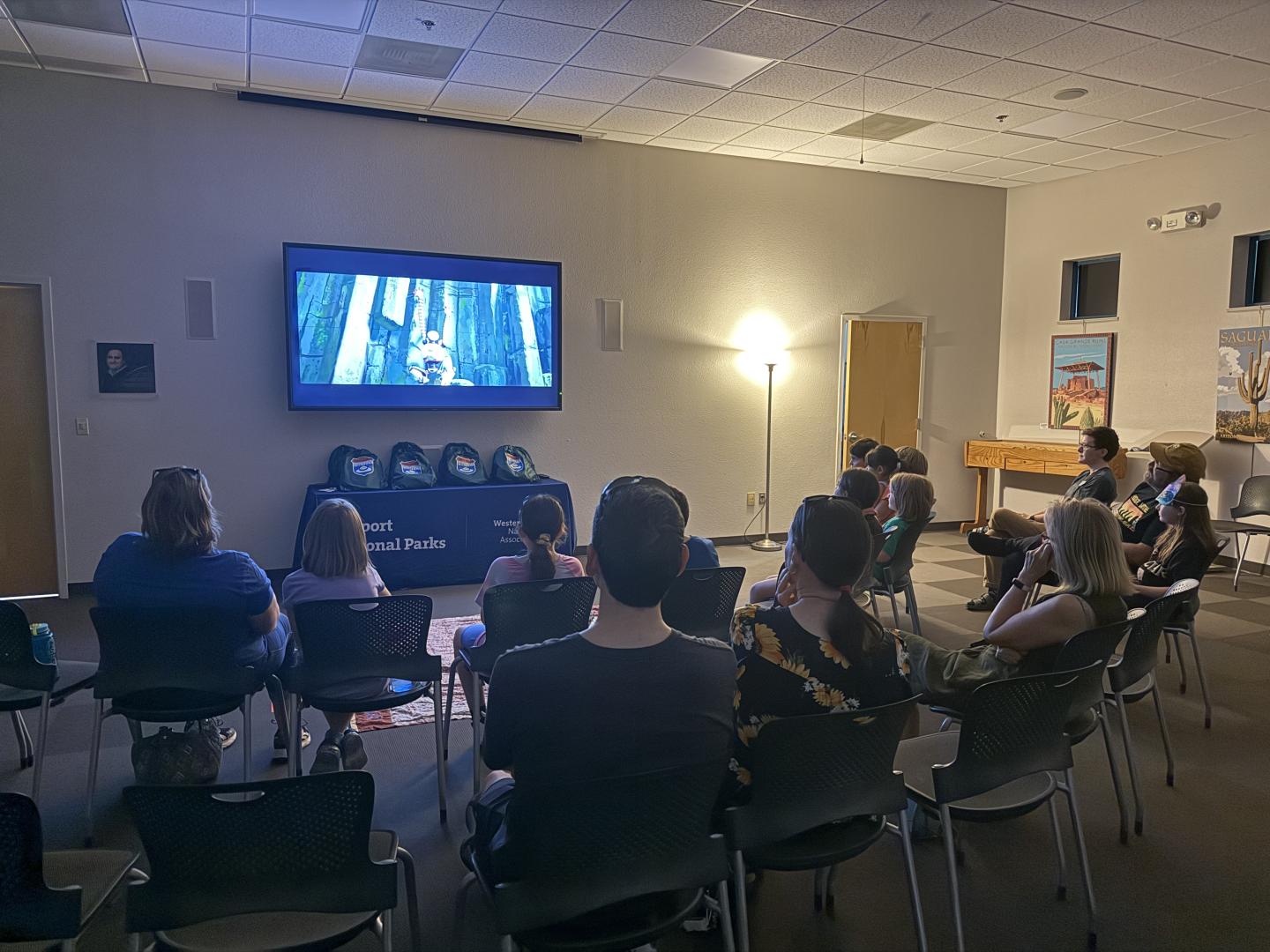 Audience watching a movie in a dimly lit room with a large screen.