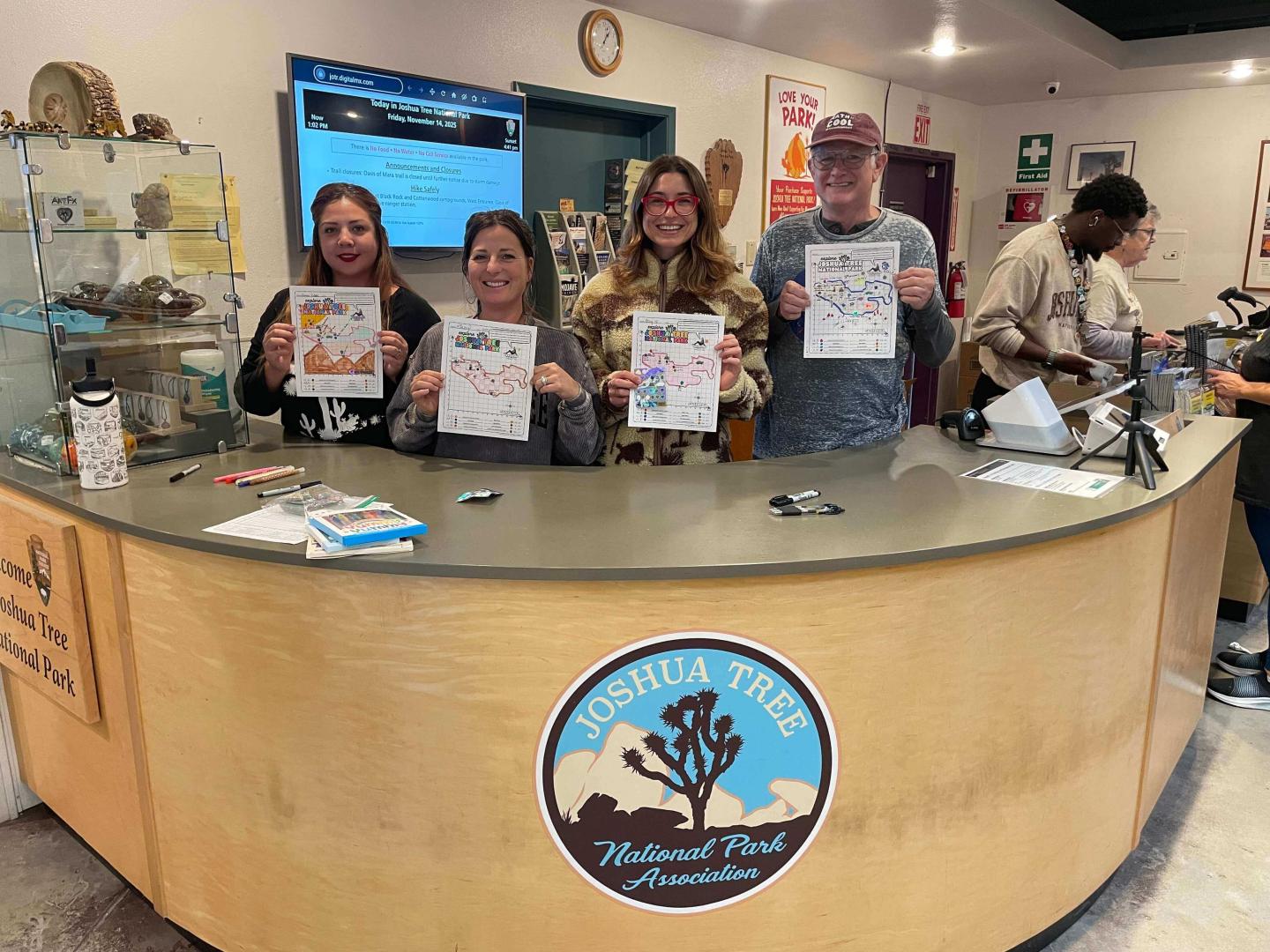 Four people smiling and holding certificates at a Joshua Tree National Park visitor center.