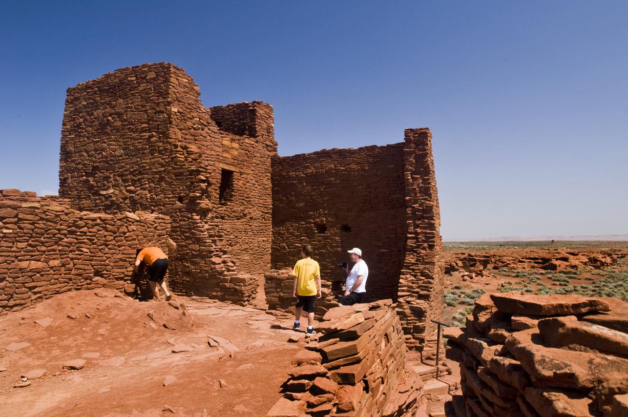 Ancient brick ruins with people exploring under a clear blue sky.