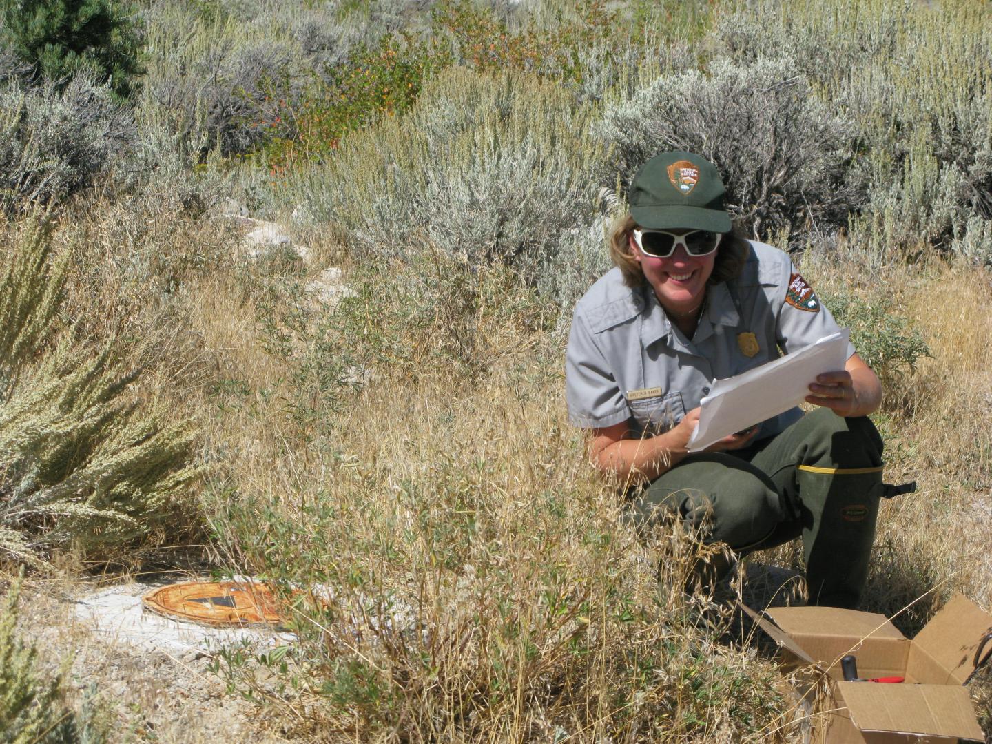 Park ranger taking notes in a grassy field.