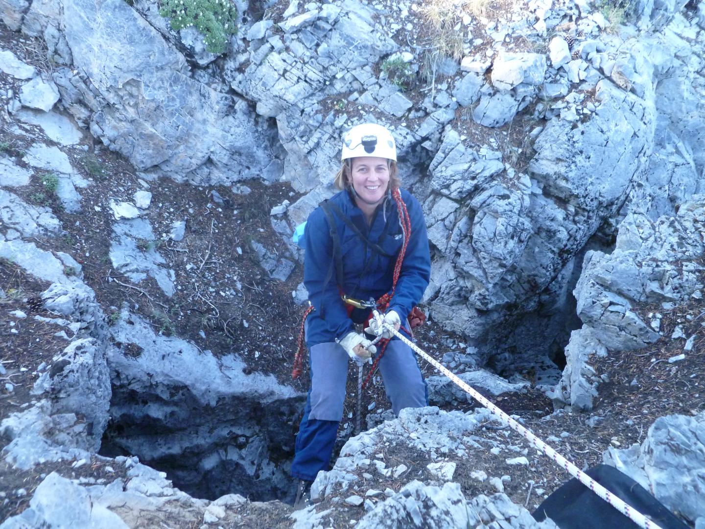 Rock climber in gear descends a rocky terrain.