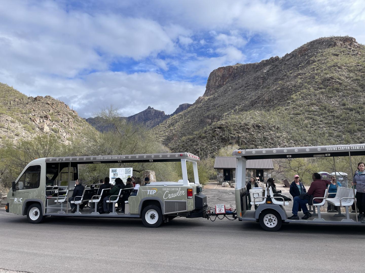 Open tram cars with passengers in a mountain landscape.