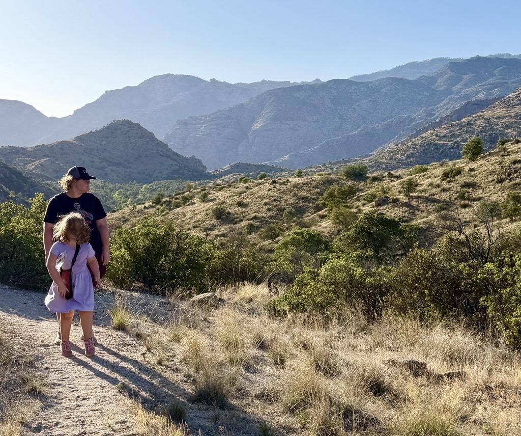 A child and adult on a mountain trail under a clear blue sky on the Arizona Trail.