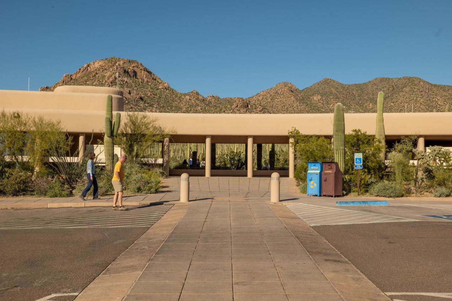 Stucco building with cacti, mountains in the background under a clear blue sky.