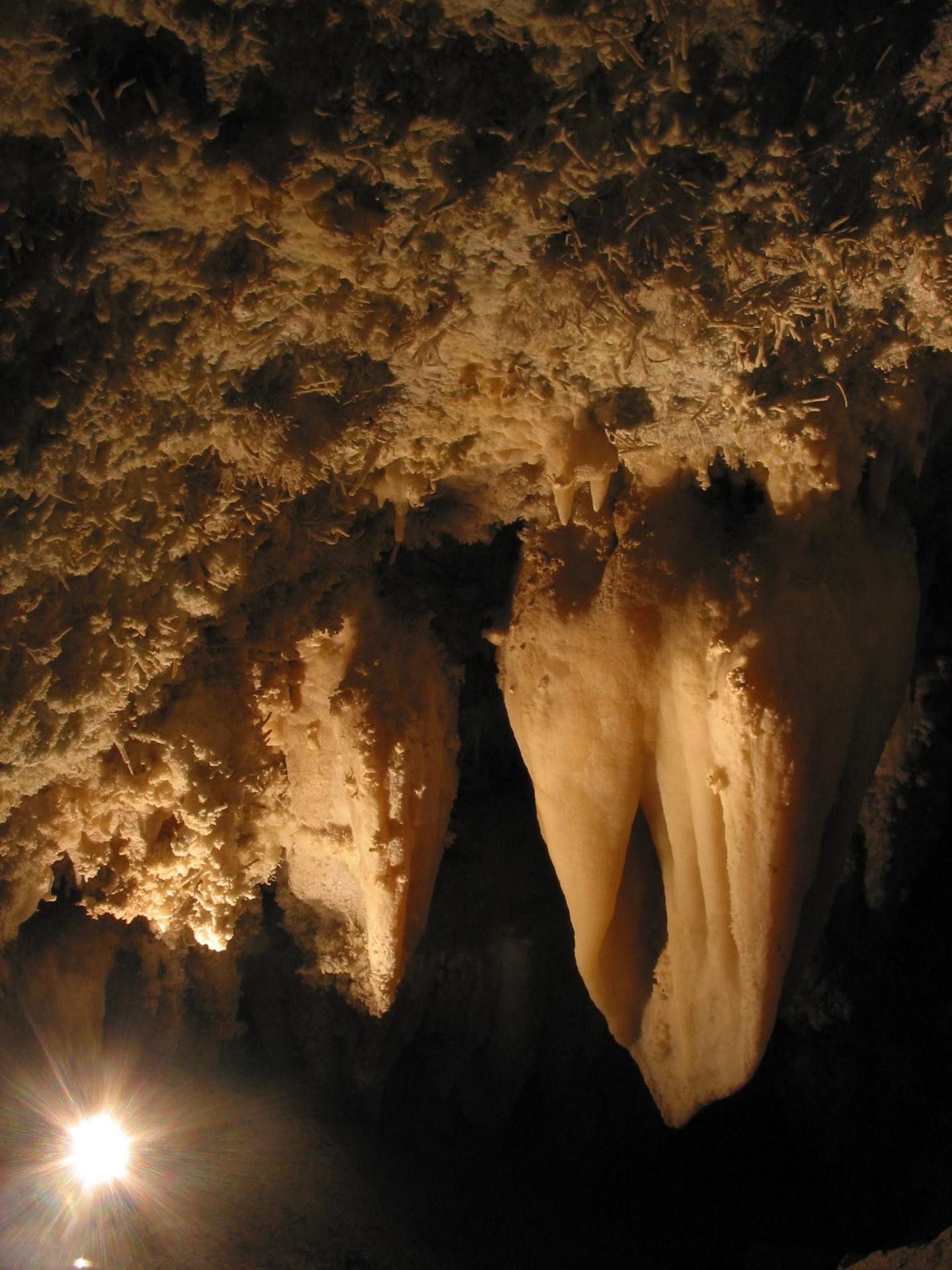 Stalactites in a dimly lit cave, illuminated by a soft light.