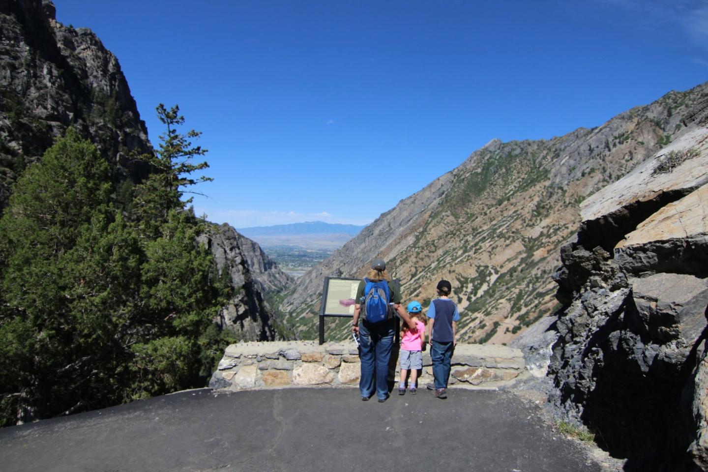 Family overlooking a scenic mountainous valley under a clear blue sky.