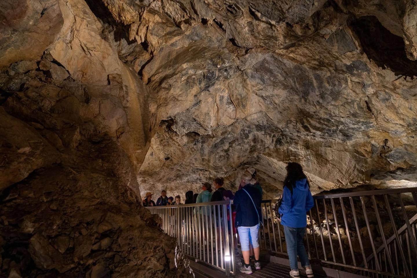 Tour group exploring a large, dimly lit cave.