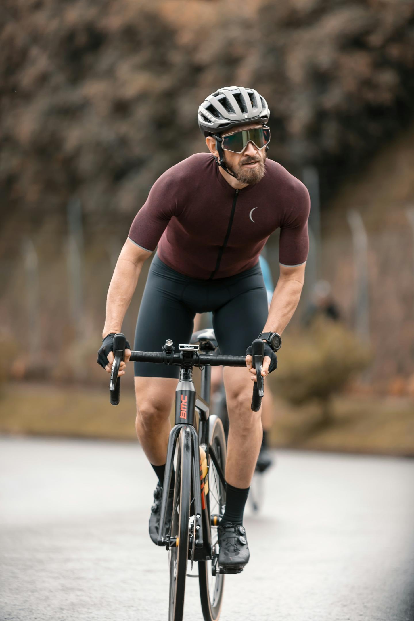 Cyclist in maroon jersey and helmet rides on a road.