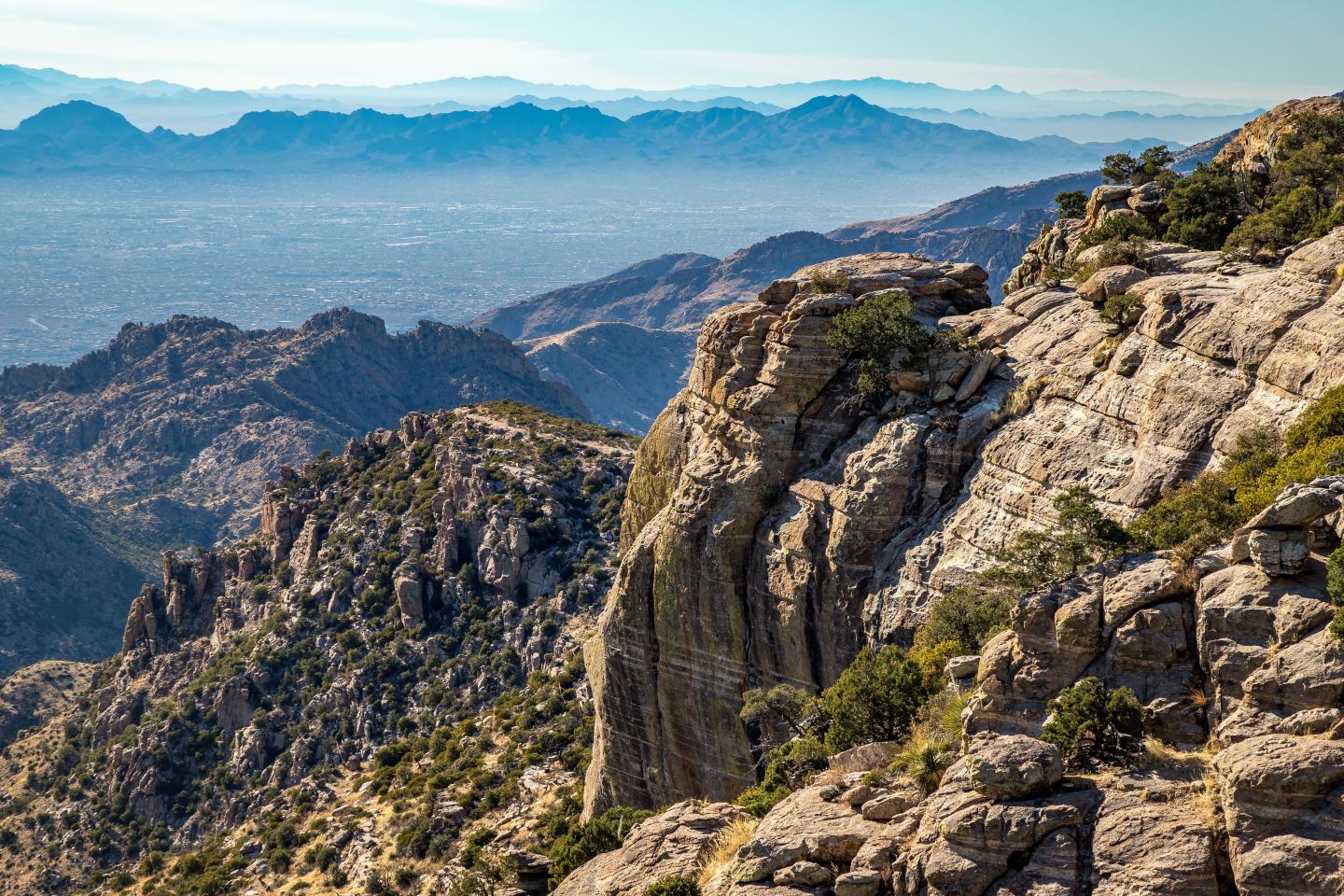 Rocky mountain landscape with distant hazy mountains and clear blue sky.